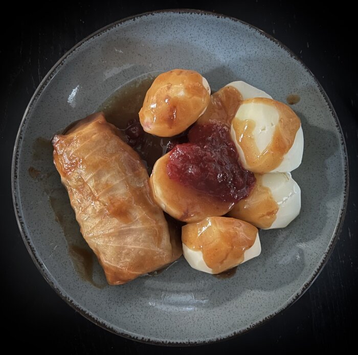 Tallrik med kåldolmar, potatis, brunsås och lingonsylt.