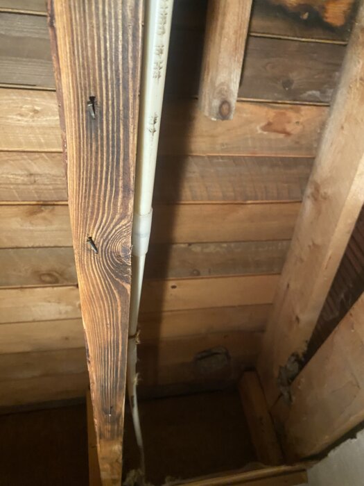 Fuktskadad träkonstruktion med synliga rör i en byggnad.