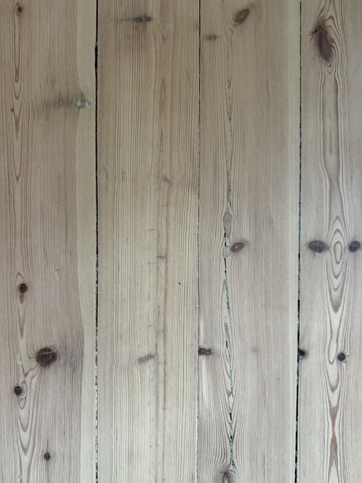 Gammalt furugolv nyslipat men med ojämt resultat, trägolvets yta visar ojämn slipning och fläckar av hårdvaxolja som börjar lossna.