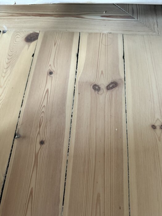 Ett slipat furugolv med tydliga brädor och viss slitage, där hårdvaxoljan börjar lossna på några ställen.