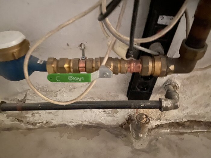 Bild av en huvudkran och rörinstallation med koppar- och mässingsdetaljer, relaterad till en diskussion om kostnader för reparation av läcka.