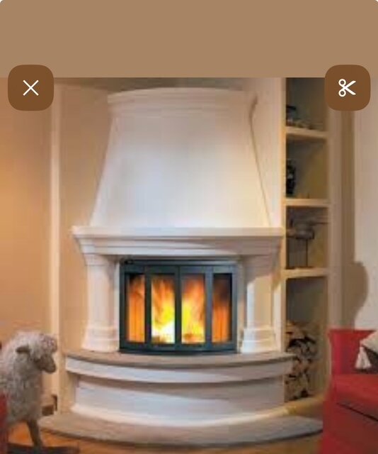 Vit, traditionell braskamin omgiven av inbyggda hyllor, med synliga vedträn och en brasa som brinner inuti glasluckan.