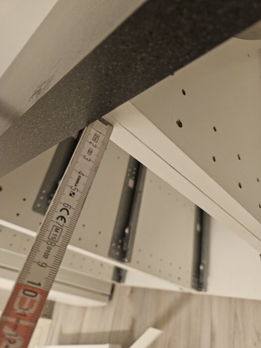 Mätning av djupet på en bänkskiva i ett kök med en linjal, visande glipan mellan skiva och väggen.