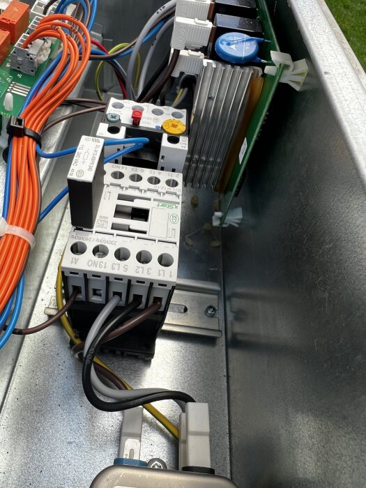 Mjukstartskort med elkablar i ett plåthölje, potentiellt kladd av lim och möjliga brända komponenter.