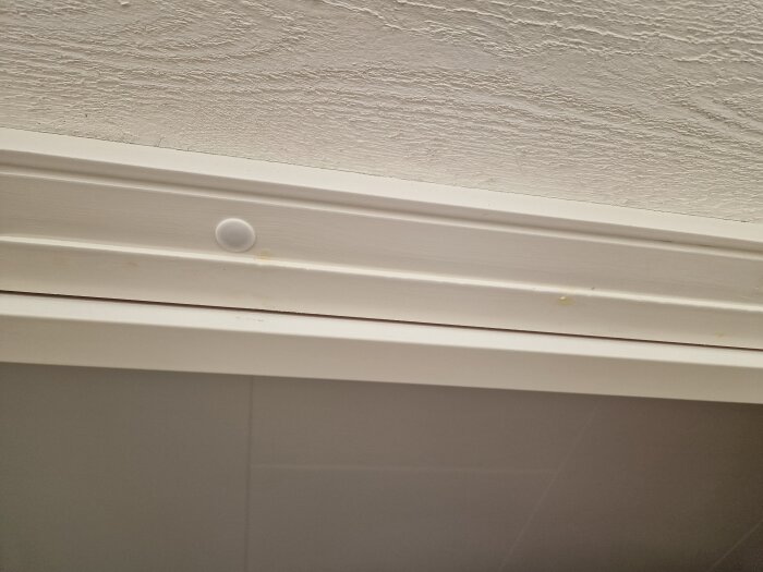 Springa runt altandörr där listerna saknas, visar plats för tidigare dörrlister som hållits med häftklammer, cirka 3.5 mm stor springa.