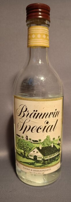Flaska med etikett på Brännvin Special, 37,5 cl, med retrodesign som visar en landsbygdsscen och tillverkad av jordbruksprodukter.