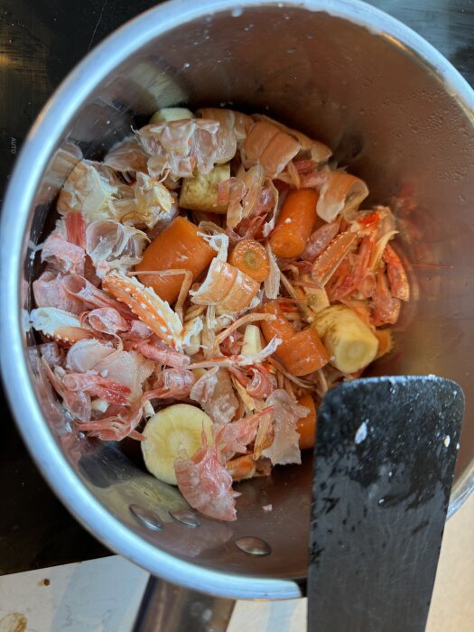 Gryta med räkor och kräftor, blandade med grönsaker i en kastrull, förberedd för att göra fisk- och skaldjursgryta.