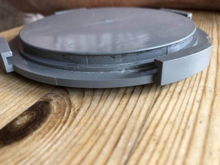 Grått plastlock till rör på träbord, visar spår för o-ring.