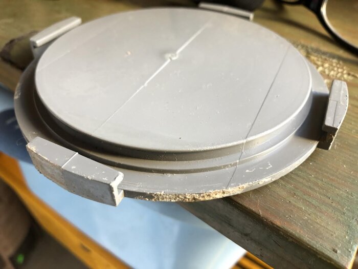 Grått plastlock liggandes på en träyta, med synligt spår för en o-ring försegling.