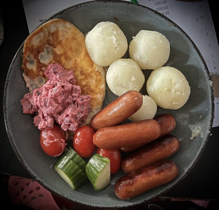 Tallrik med prinskorv, kokt potatis, omlett, rödbetssallad, körsbärstomater och gurkbitar.