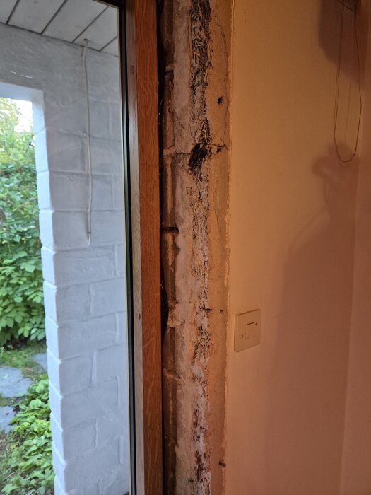 Ytterdörrens insida med synlig vassmatta och puts runt karmen i ett äldre hus.