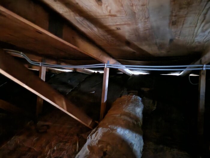 Plywoodtak i en vind med synliga reglar och hängande isolering, visar begränsad takfotventilation.