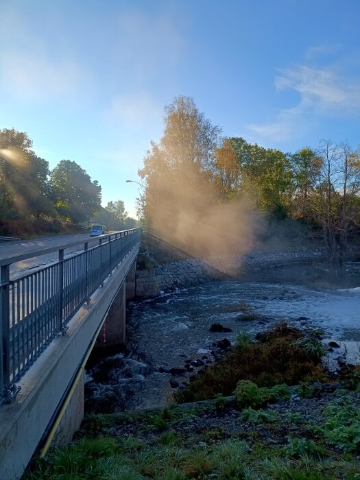 Bro över Eskilstunaån en solig höstdag med grönskande omgivning.