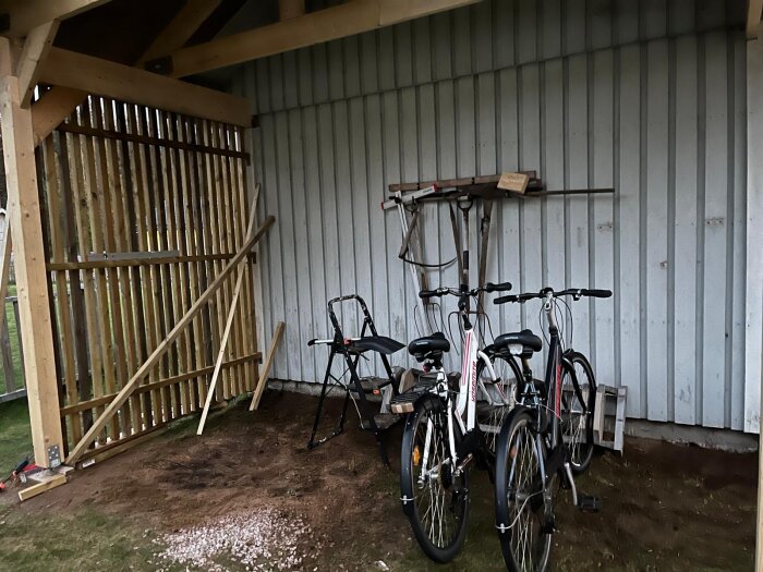 Carport med vertikala träreglar som skydd, två cyklar lutade mot en vägg, verktyg i bakgrunden. Tester gjorda med impregnerade ribbor.