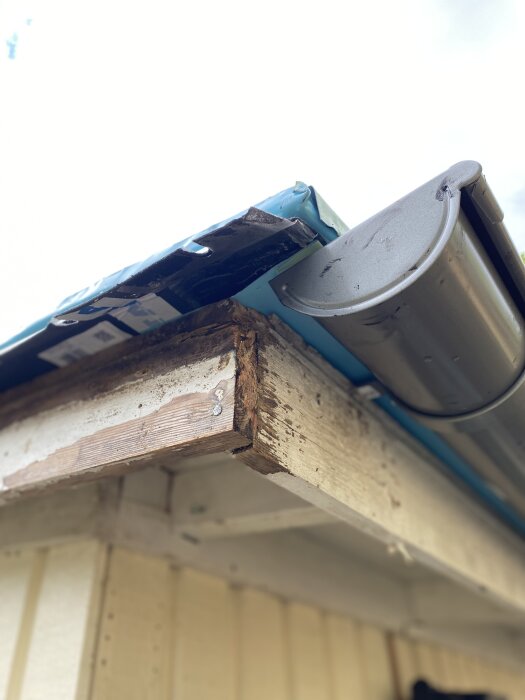 Närbild på ett hus där vindskivorna har tagits bort för målning och takrännan ovan är synlig.