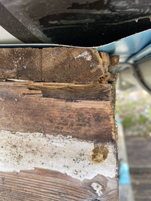 Rostig vindskiva efter borttagning för målning, med spår av slitage och smuts, bredvid en skorsten med omvänd glipa.