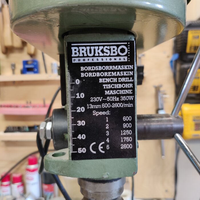 Etikett på en Bruksbo pelarborrmaskin med specifikationer och hastigheter i en verkstadsmiljö.