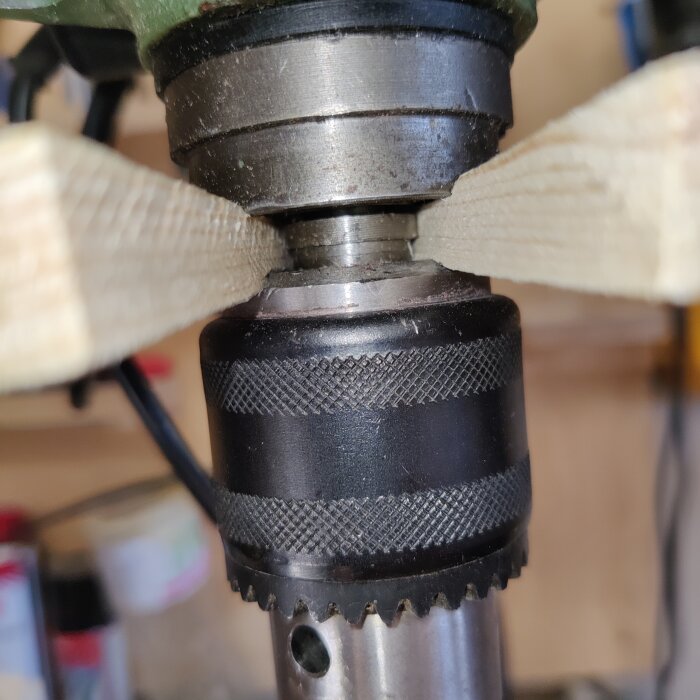 Borrmaskin med träbitar fastspända i chucken, används i byggprojekt.