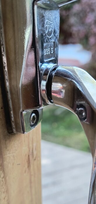 Närbild av ett kromat dörrhandtag monterat i trä, med synlig glipa mellan handtag och dörr.