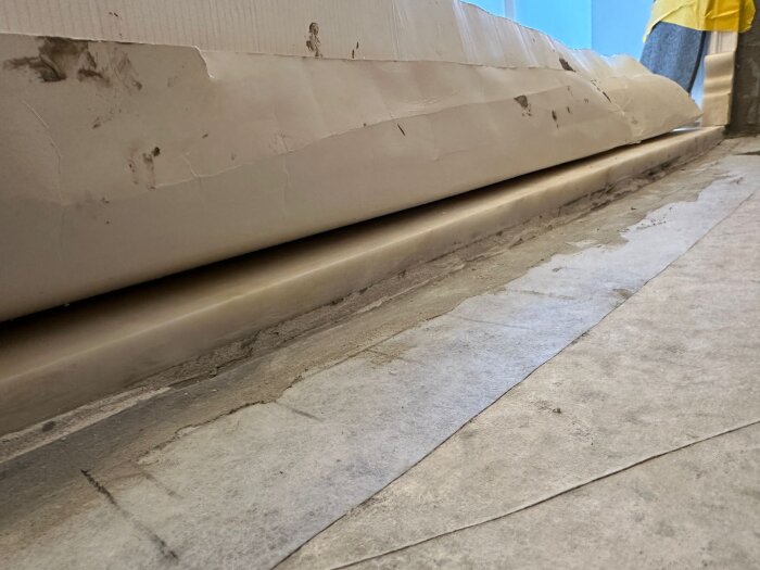 En plats förberedd för installation av en marmorplatta, med synliga byggmaterial och en skyddspapp vid kanten.