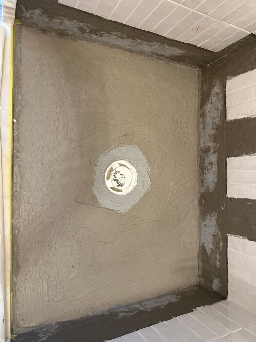 Förberett område med kaklat golv och vägg, rund hålighet i mitten, redo för marmorplattan att läggas av stenläggare.