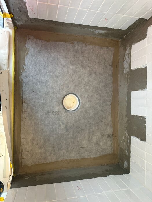 Byggprojekt som visar ett duschgolv med nylagd platta och förberedelser för att installera marmor i badrummet.
