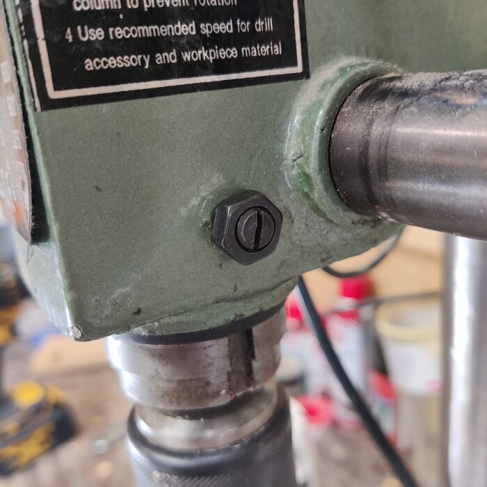 Bult på sidan av en grön maskin, sannolikt en del av en borrmaskin, i en verkstadsmiljö.