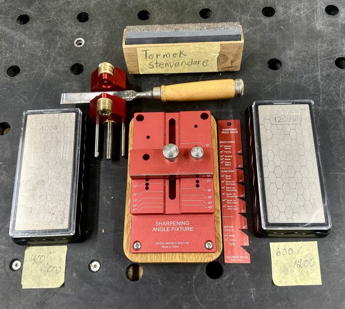 Slipjigg med två slipstenar, ett stämjärn och en slipguide för olika vinklar. Märkta som 400# och 1200# på arbetsbord.