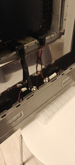 Isärtaget köksfläktsaggregat med synliga ledningar och komponenter, på ett vitt bord.