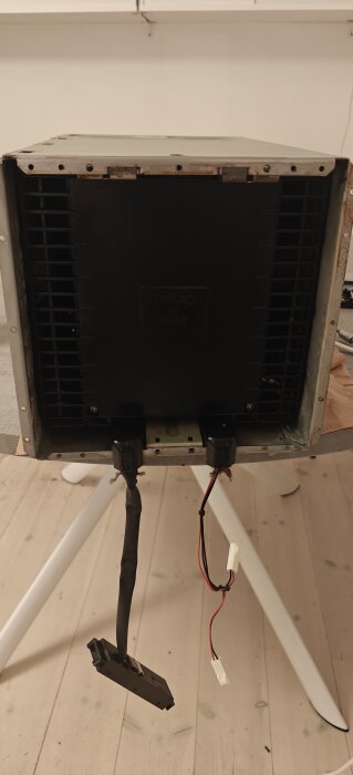 En demonterad köksfläkt med synliga kablar och sladdar, placerad på ett bord inomhus.