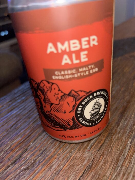 Brun-flaska av Amber Ale från Dry Dock Brewing Co, placerad på ett träbord.