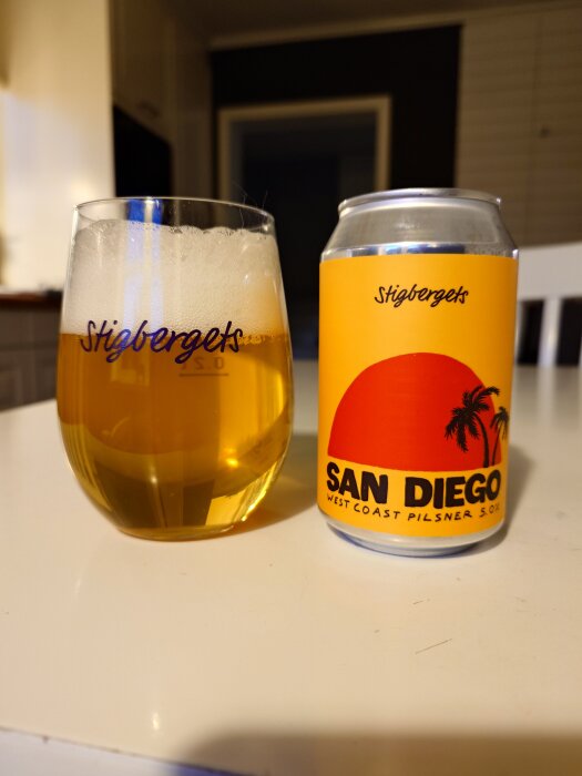 En glas öl från Stigbergets bredvid en burk med etiketten "San Diego West Coast Pilsner" på ett bord i köket.