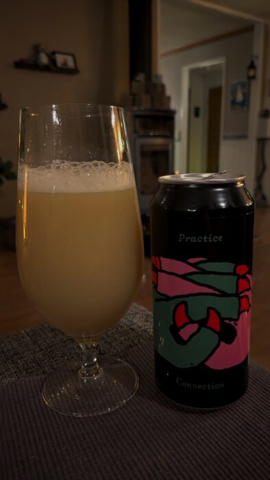 Burk och glas med öl Omnipollo/Verdant Practice Connection, ljusgul dryck med skum, i en hemtrevlig miljö.