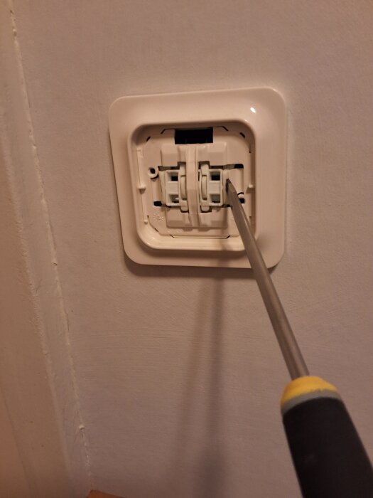 Användning av skruvmejsel för att lossa en knapp på väggen.