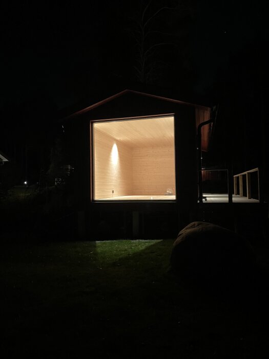 Upplyst interiör av byggnad på natten, med synligt innertak och väggar i trä. Belysningen är nyinstallerad.