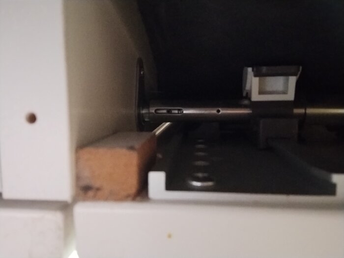 Diskmaskinens lucka sedd underifrån med små träklossar fastlimmade på sidorna för att centrera luckan och justera dess position.