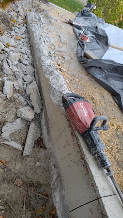 Rivningsarbete av betongmurar med ett elverktyg, omgärdat av krossat betongspill på marken.