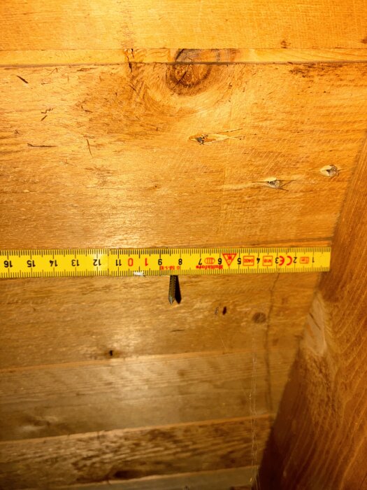 Måttband på en trävägg som visar avståndet mellan 9 och 10 cm.