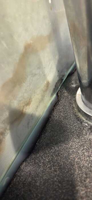 Fogar kring köksbänkens glasskiva med missfärgningar och tecken på fuktskador. Fogen är delvis borta vid blandaren.