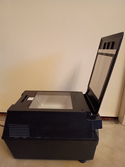 Projektor för genomlysning av trasiga pappersbilder placerad i rum med dämpad belysning.