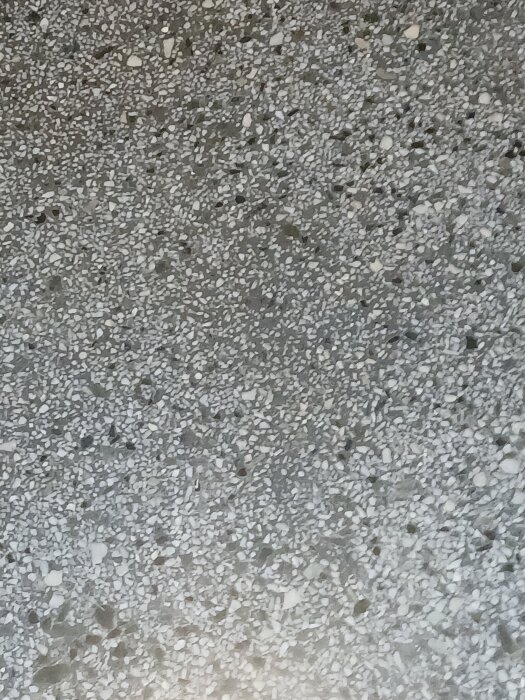 Golv i uppgång med terrazzo-liknande yta från ett hus byggt 1957, visar grått och vitt krossat material, fråga om våttorkning som städmetod.