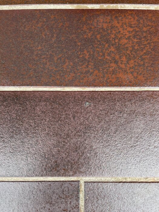 Mörkbruna klinkerplattor med texturerad yta och ljusare fogar, troligen för utomhustrappa.