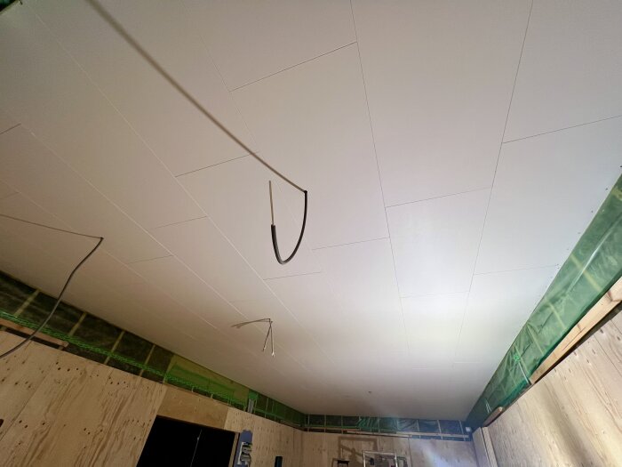 Nyinstallerat vitt tak med synliga ledningar i ett rum under renovering.
