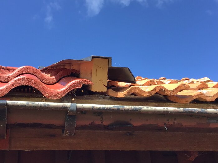 Rött tegel- och plåttak med kloss under, felaktig montering visar att plåten inte vilar korrekt på vindskivan, diskuterat av husägare.