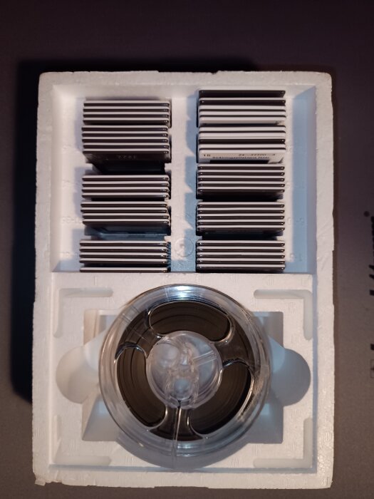 Rullband i förpackning med flera magnetiska kassetter ovanpå, antagligen för en gammal Tandberg rullbandspelare.
