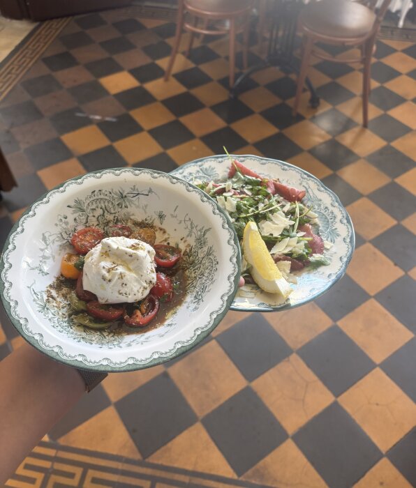 Tvårätters serverat ovanpå ett rutigt golv med orange och svarta rutor i gammaldags stil, liknande det i Ystads gamla stationshus.