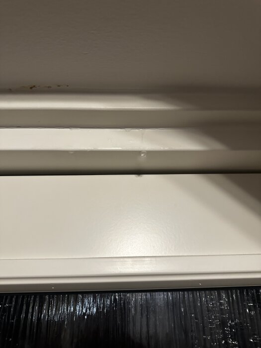 Droppande vatten från innertak vid dörrkarm, antyder läckageproblem ovanför ytterdörr placerad vid gavel på radhus.