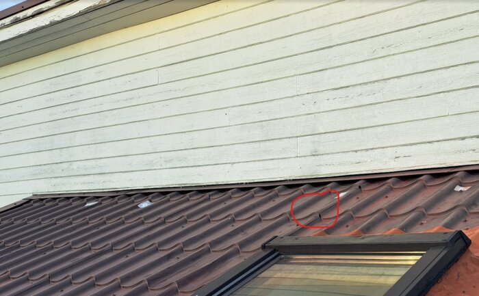 Takläckage markerat med rött på takpannor vid vägganslutningen. Eventuellt vattenintag vid panelskarv eller under väggplåt.