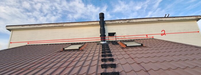 Plåttak med två röda pilar och siffror markerade på en vägg ovan taket, visar avstånd för eventuell plåtöverlapp från tak till panel.