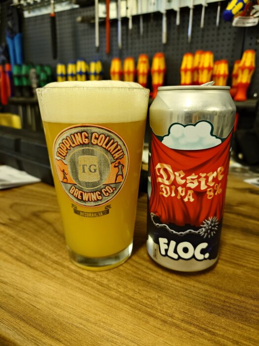 Ett glas med IPA och en ölburk med texten "Desire" på ett bord i ett garage med verktyg i bakgrunden.
